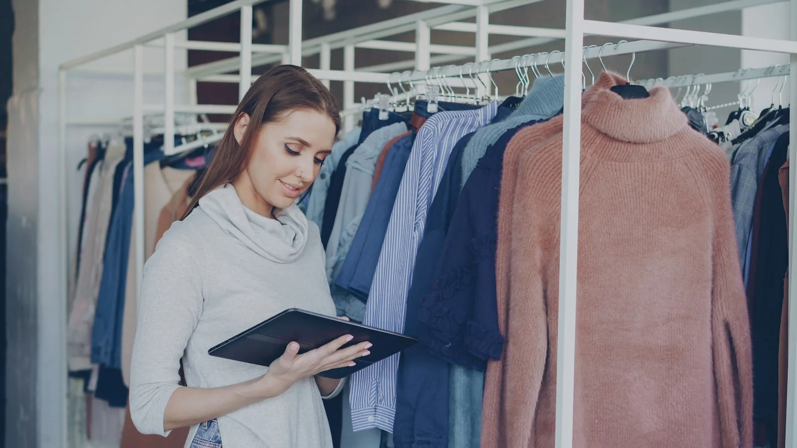 Une commerçante consulte sa tablette dans sa boutique de vêtements