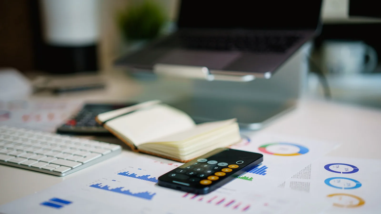 Un bureau avec calculatrice, ordinateur portable et documents de graphiques de coûts